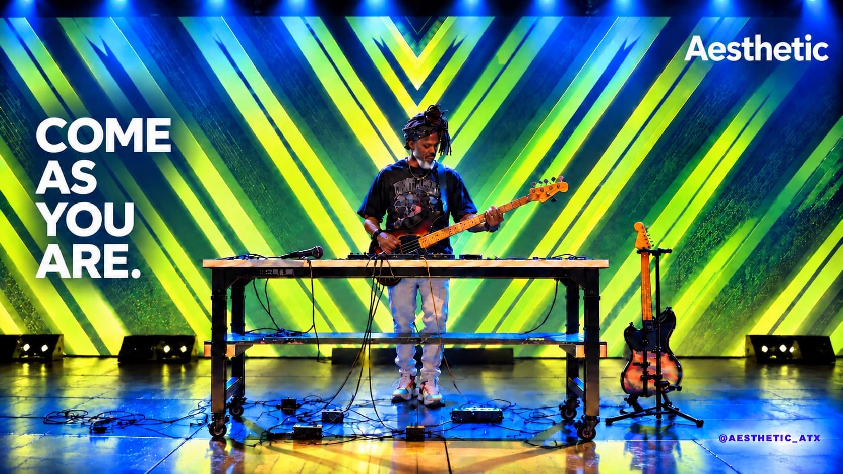 A musician plays bass on stage at a table of pedals, in front of green and yellow chevron projections, beside the words come as you are