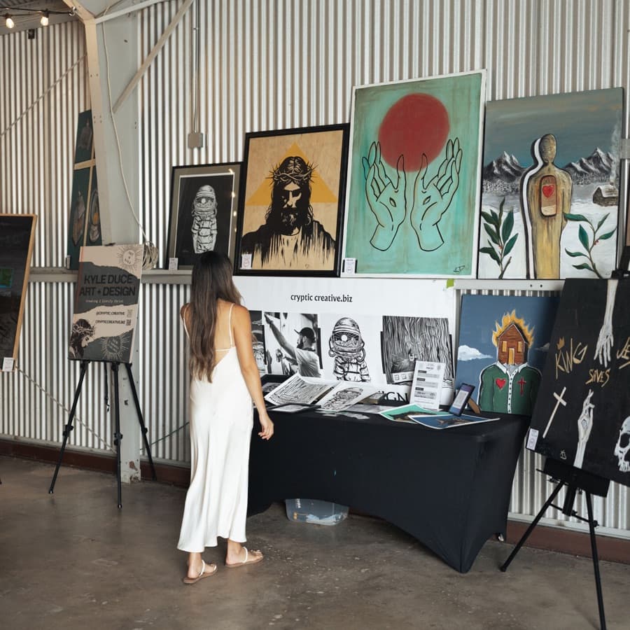 A woman looks at a wall of paintings at an Aesthetic art night.
